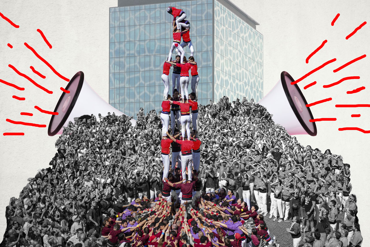 Tower of people holding each other up with giant megaphones either side of the crowd 