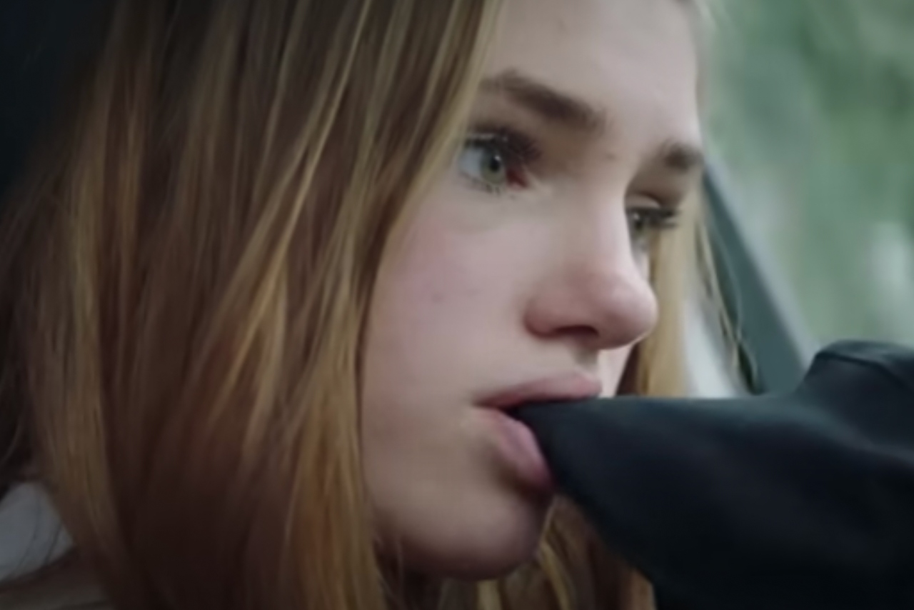 A young girl chews on the sleeve of her hoodie