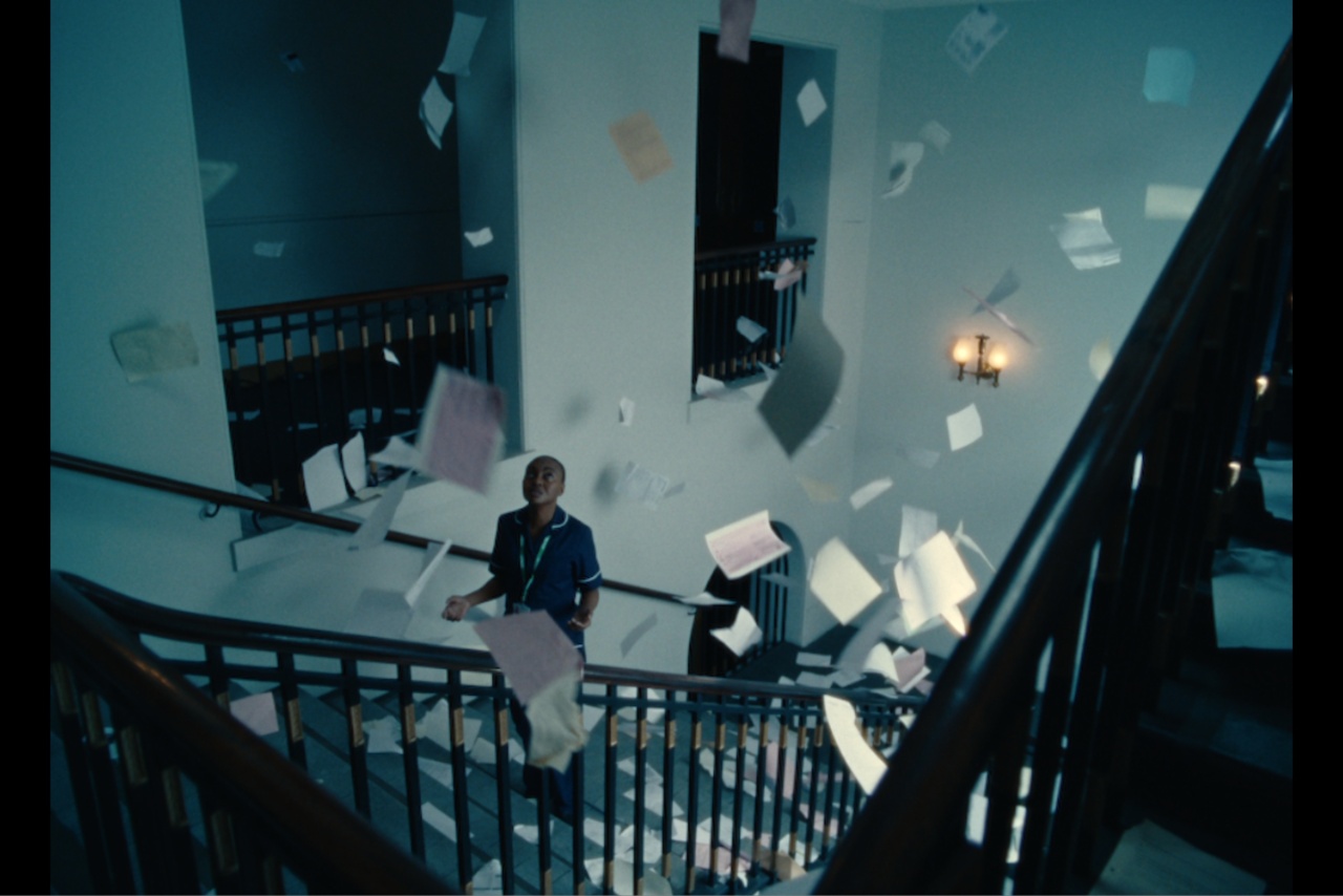 Macmillan nurse standing on stairs with paper falling around her