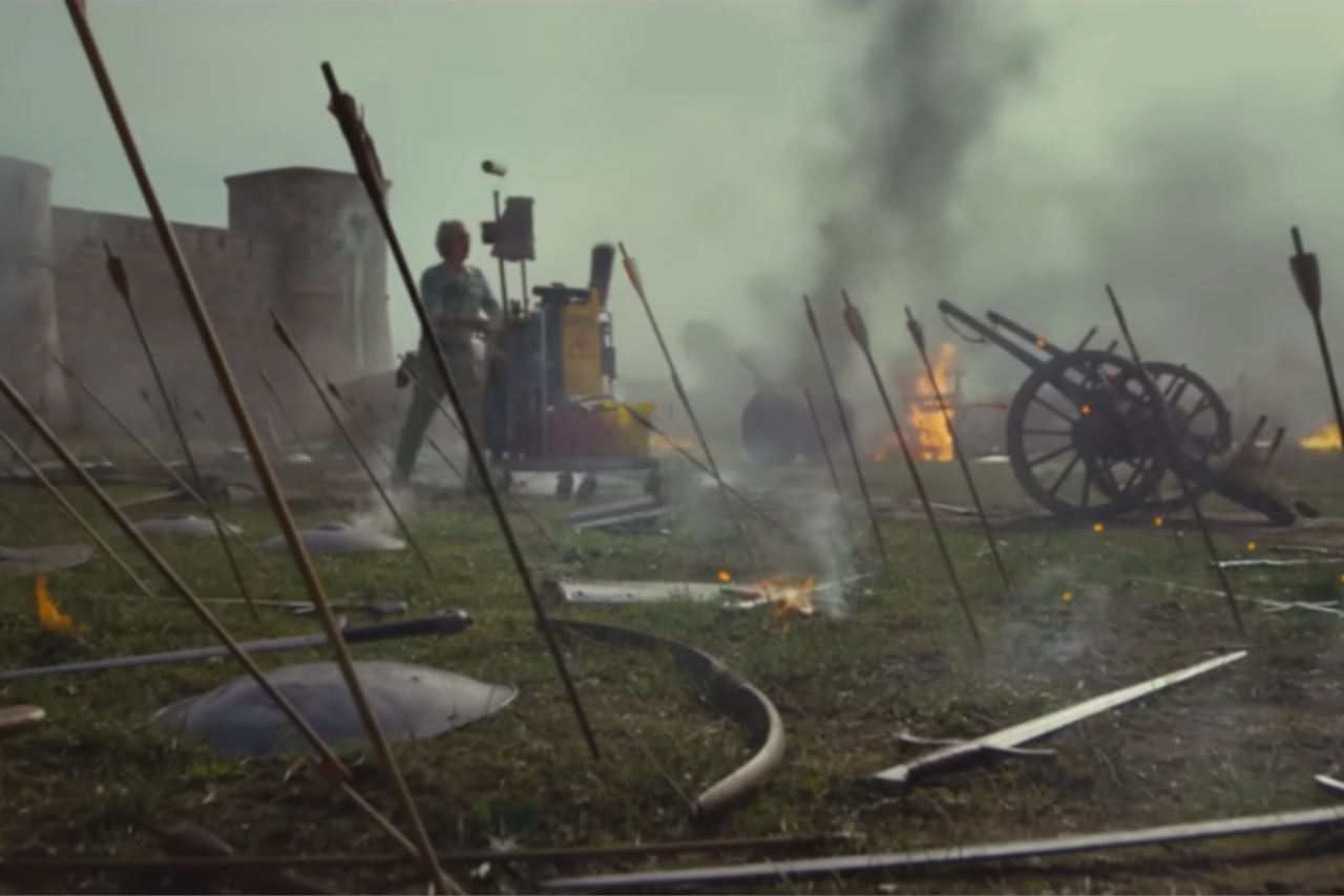 Arrows stabbed into grass and cleaner walking in background with cleaning materials on a wheeled trolley