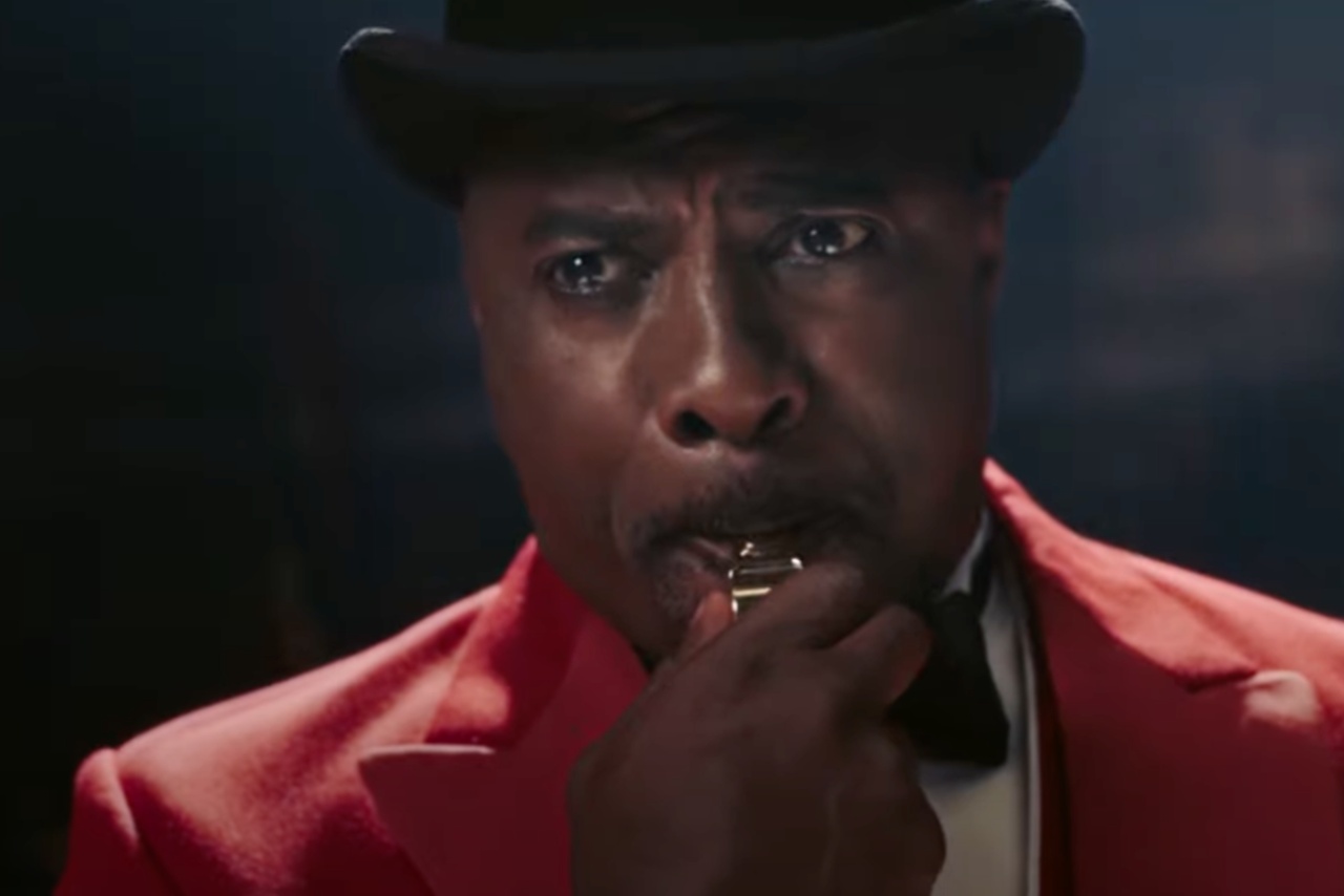 Idris Elba dressed as a ringmaster blowing a whistle