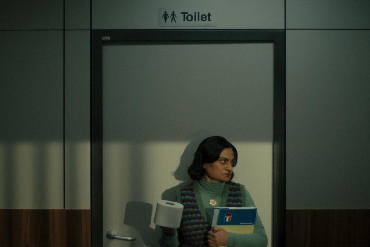 A woman goes to toilet with loo roll and dictionary at work