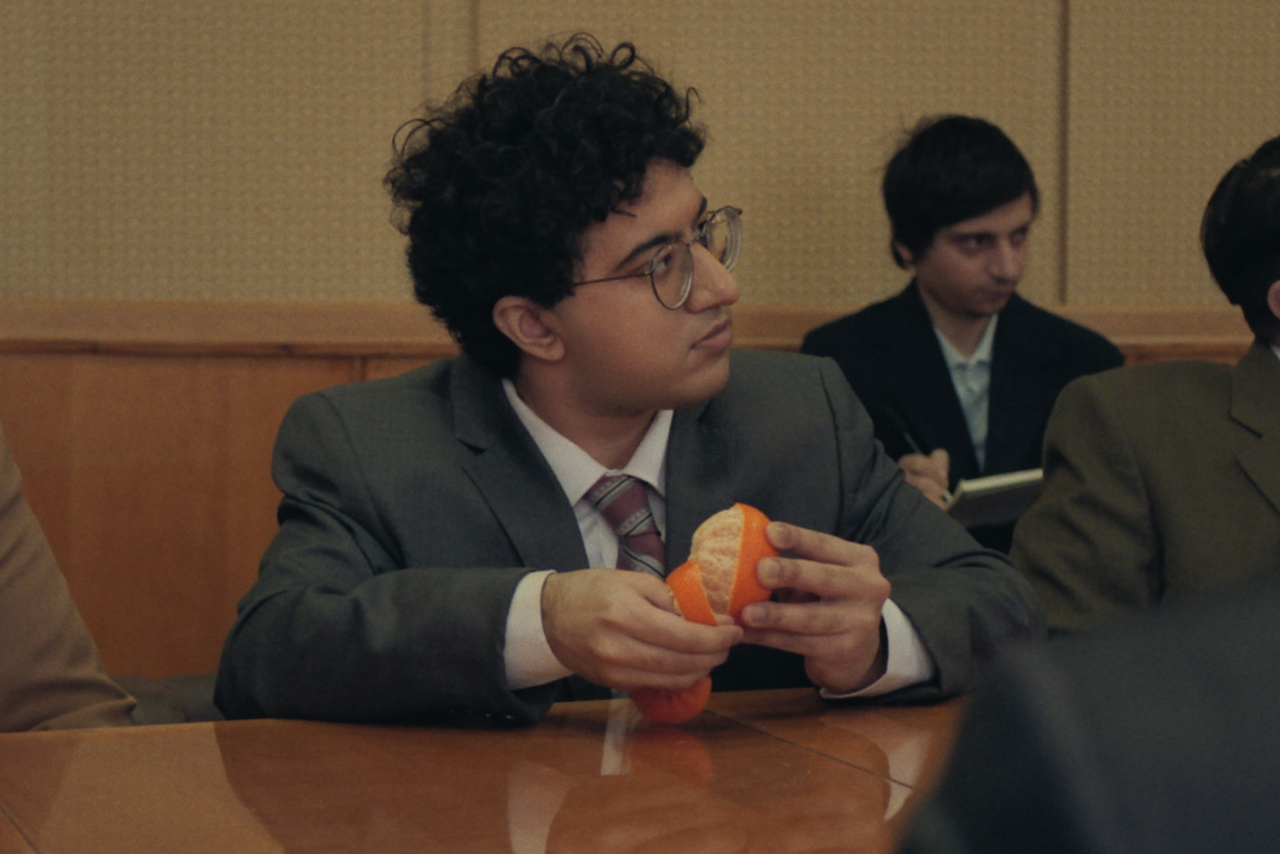 A young collegue peels a satsuma in a beige office space