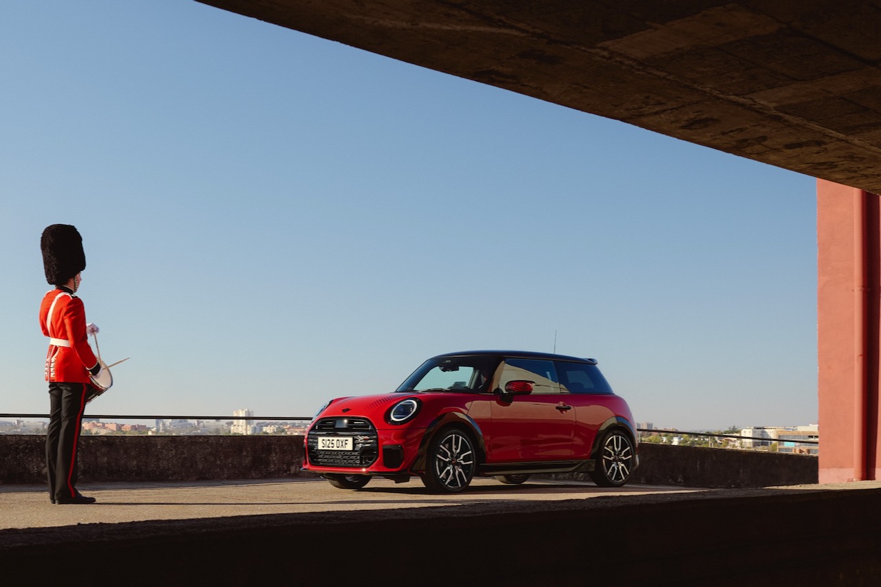 Scots Guard stands beside a Mini Cooper car