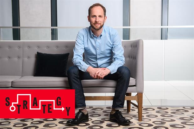 A colour full body shot of Publicis' Josh Bullmore sitting on a sofa with the word 'strategy' in a red box in black writing